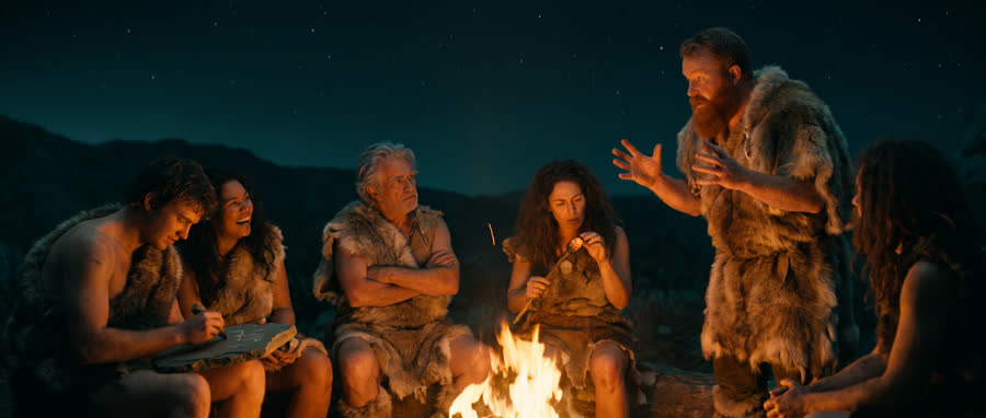 Autour du feu, l'homme des cavernes explique son idée à la tribu.